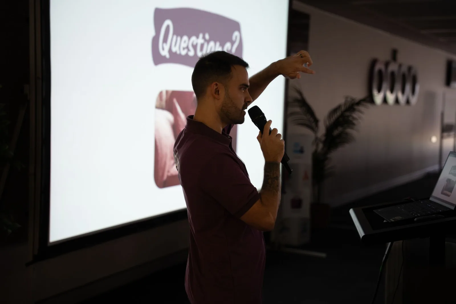 Доповідач з мікрофоном на сцені перед екраном з написом «Questions?» під час Partner Day 2026